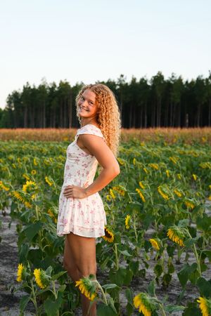 Joyful summer portrait session among sunflowers with floral dress and natural lighting.