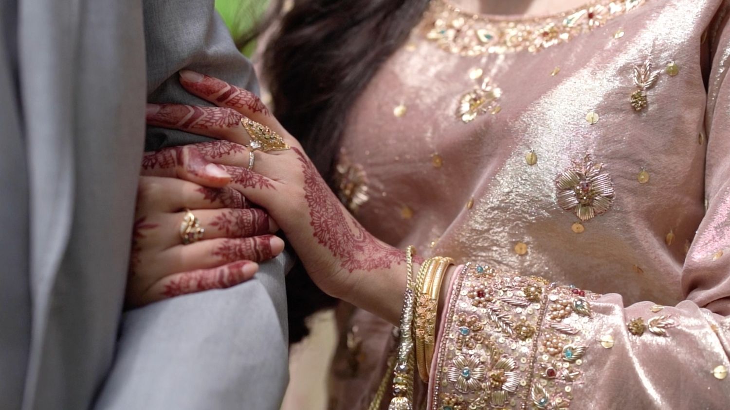 Close-up of intricate gold embroidery details on pink wedding attire.