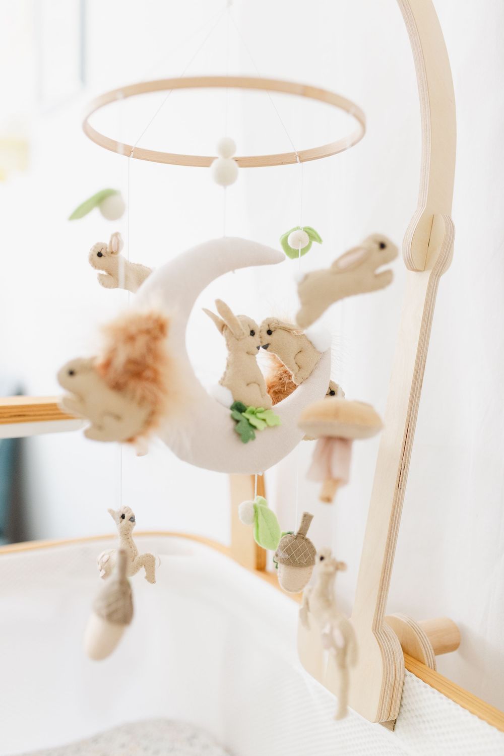 A collection of plush bunny toys hanging from a white mobile above a crib creates a soft nursery decoration.