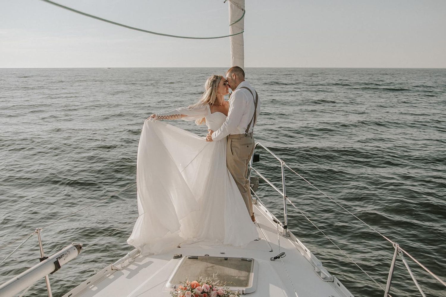 Couple sharing romantic moment on sailboat against ocean backdrop.