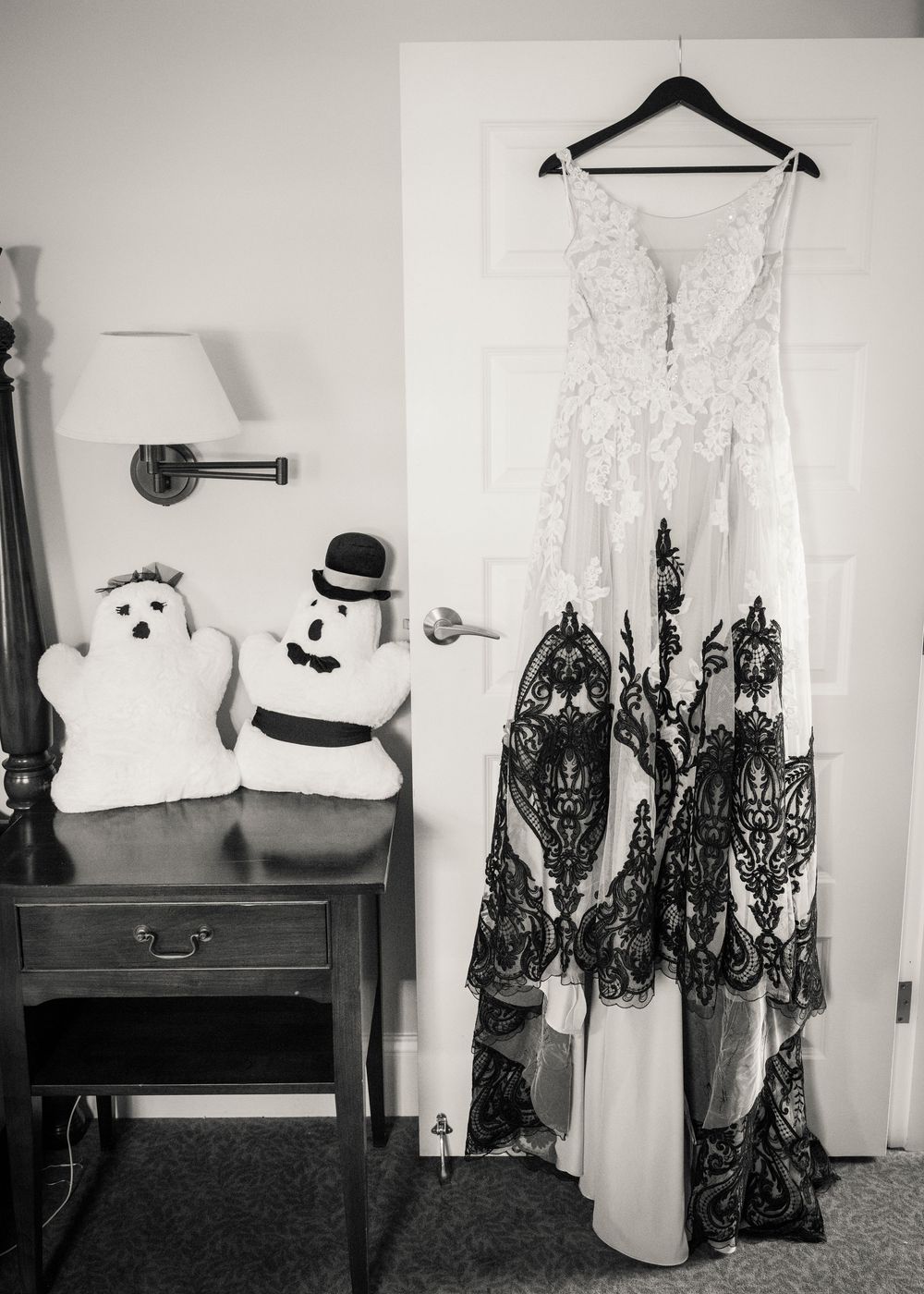 Wedding dresses and formal attire hanging on display with plush white decorative items on a shelf.