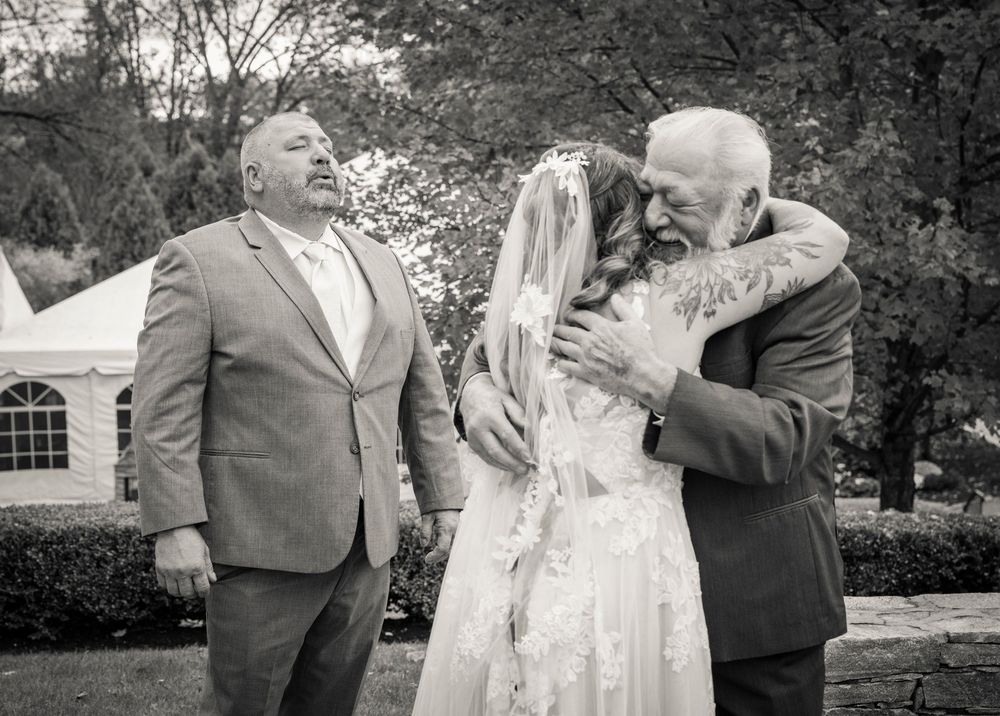 Emotional black and white candid wedding moment shared between family members in an outdoor garden setting.
