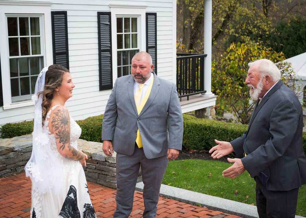 Candid outdoor wedding moment captured on a brick patio in front of a white house.
