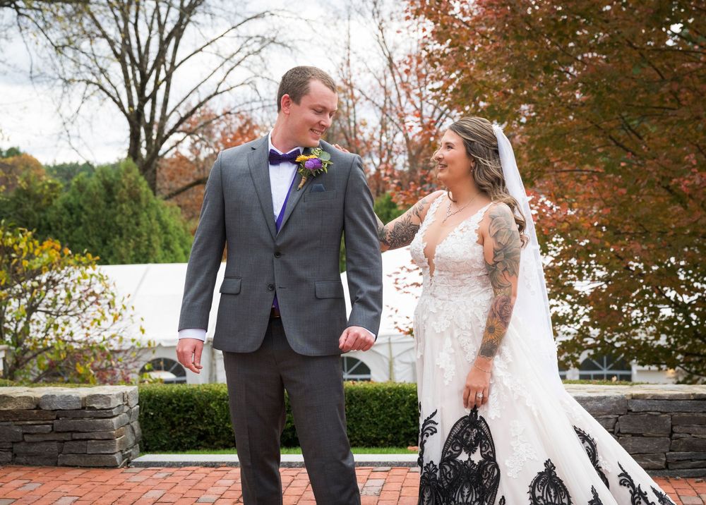 A couple shares a romantic moment in front of autumn trees during their wedding photo session.