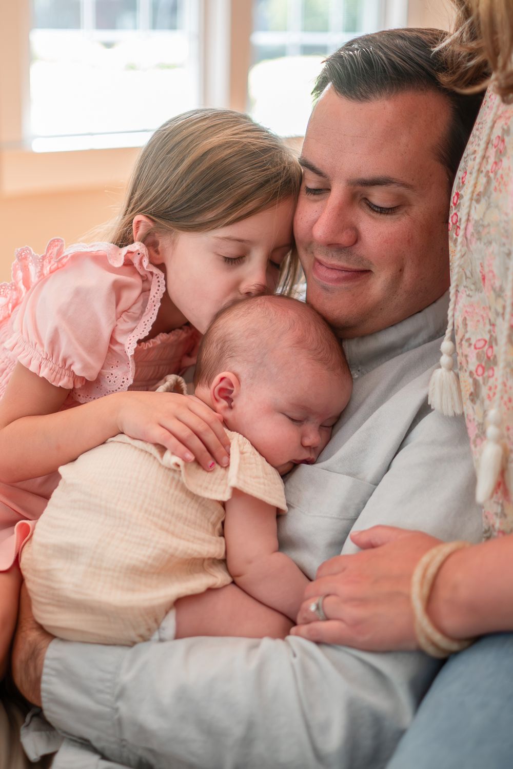 A series of tender moments showing parents cuddling with their sleeping newborn baby on a couch.