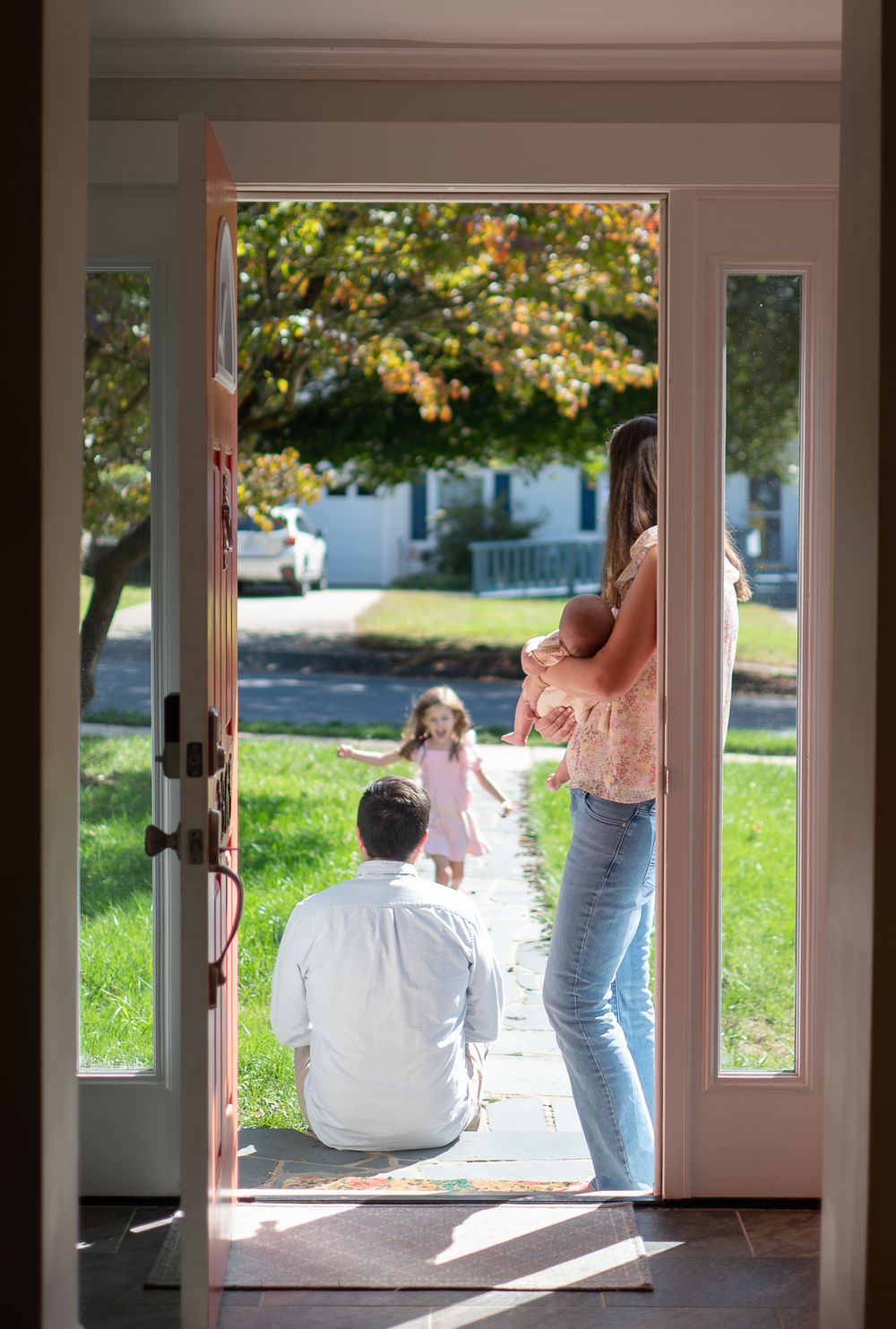 People sit in a bright sunlit doorway or entrance area of a building, creating a peaceful indoor-outdoor scene.