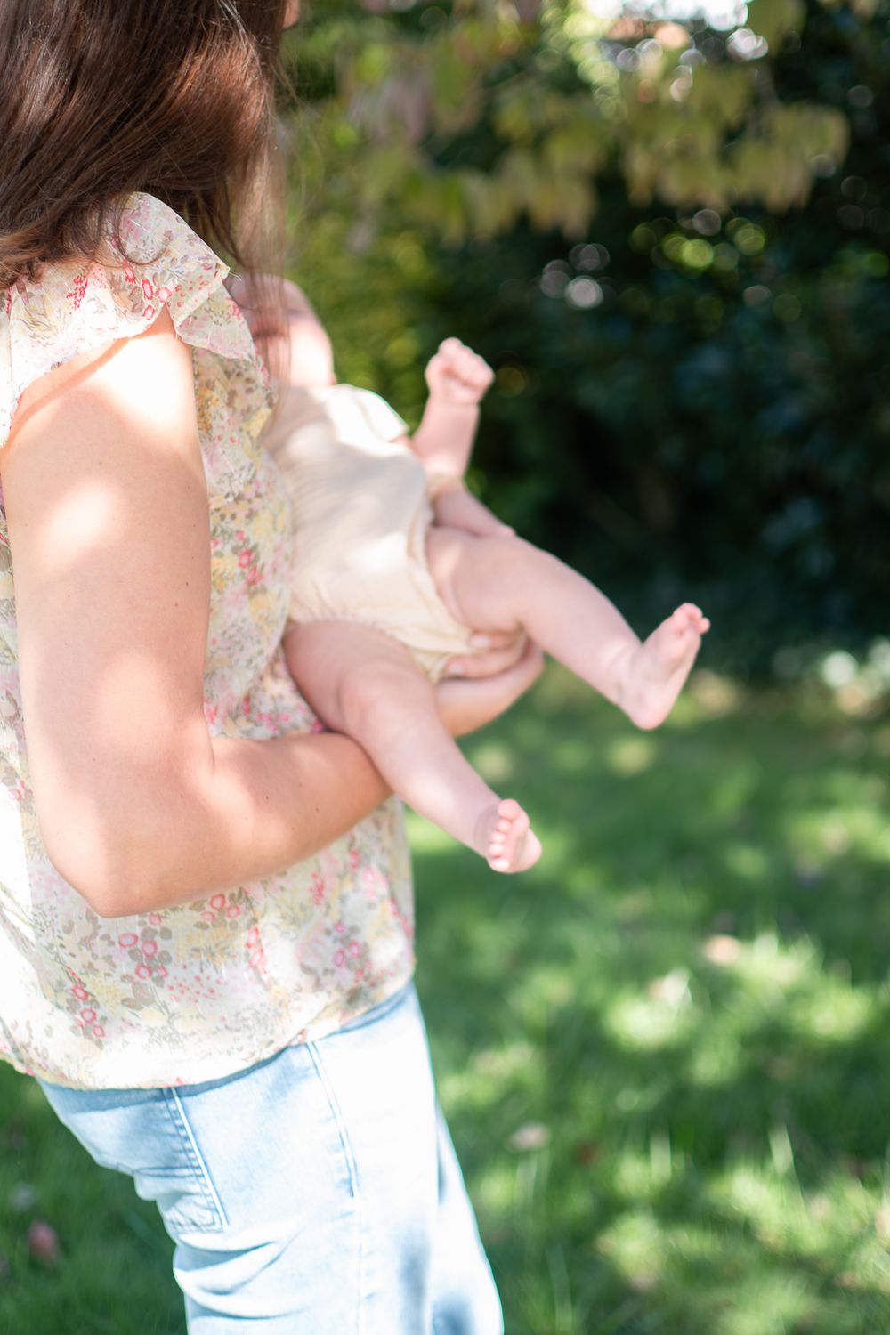 A series of outdoor photos showing a baby in a floral top and jeans against a sunlit garden background.