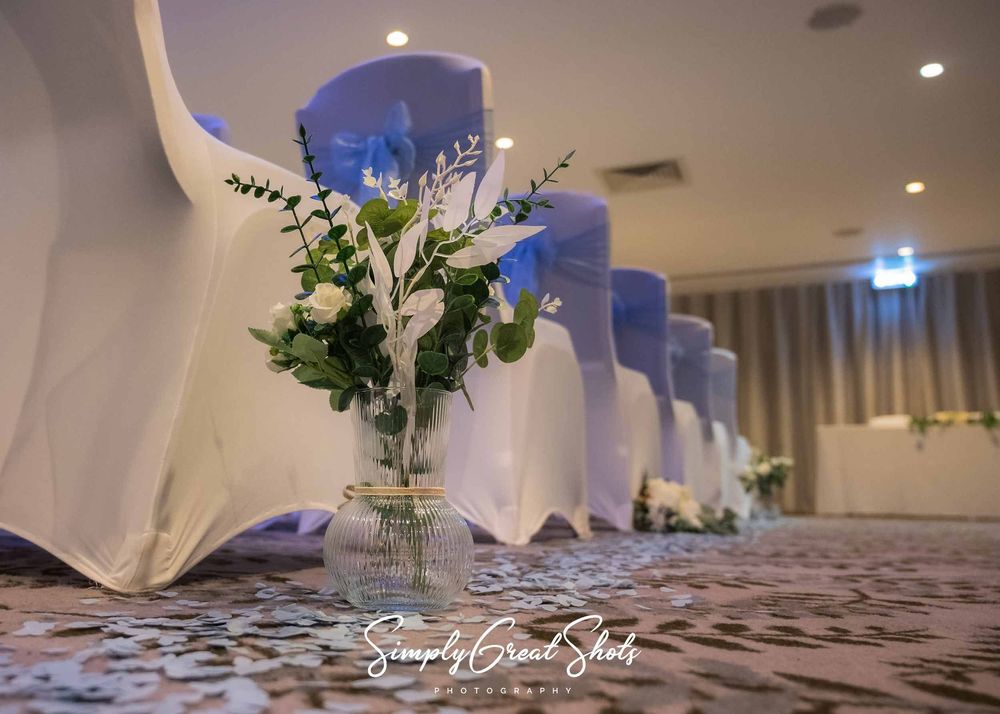 BowdenHall wedding photographer captures a vase with white and green foilage and and blue and white petals on the floor.