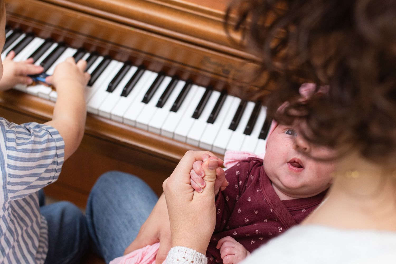 Mom holds newborn while song plays at the piano