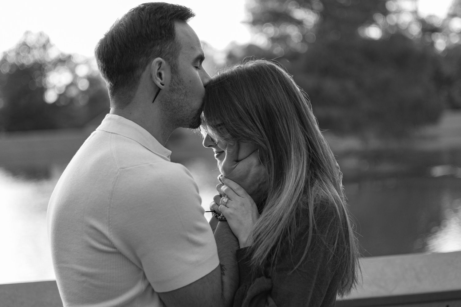 Couple embracing outdoors beside a lake during a romantic couples photography session, captured in black and white.