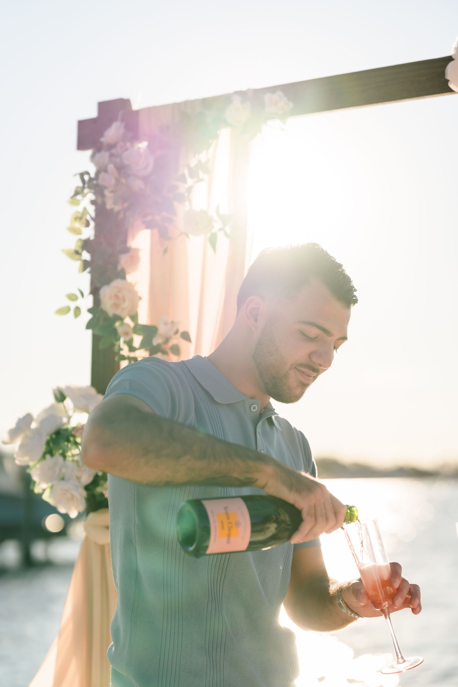 Pouring champagne during sunset celebration by the ocean.