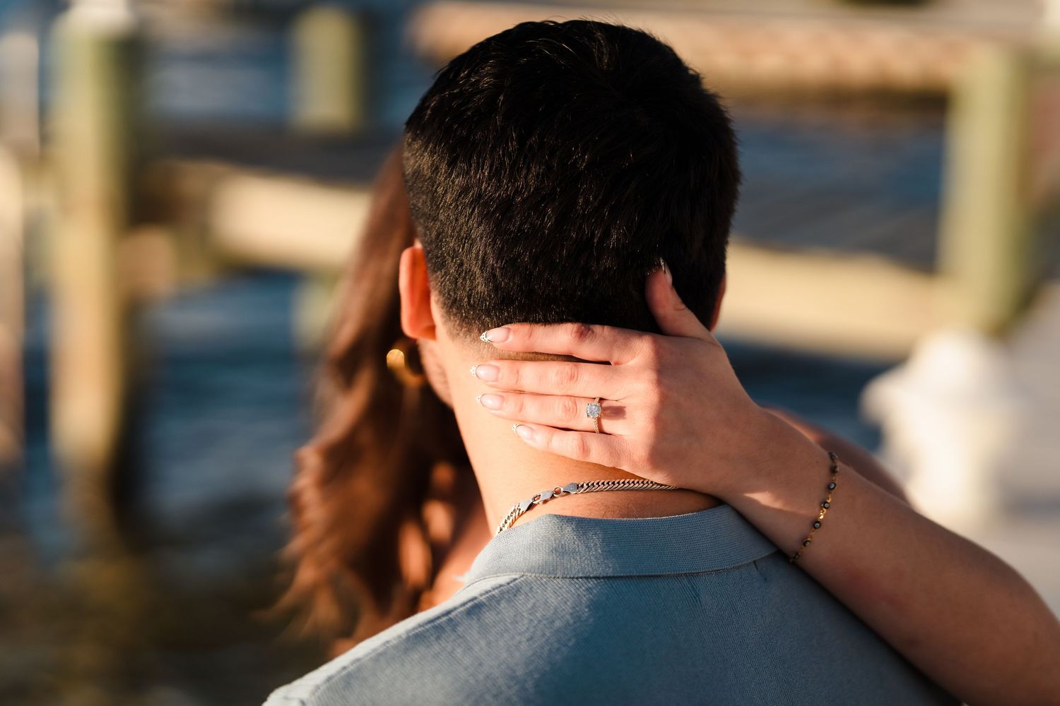 An intimate waterfront engagement photo showing affectionate embrace.