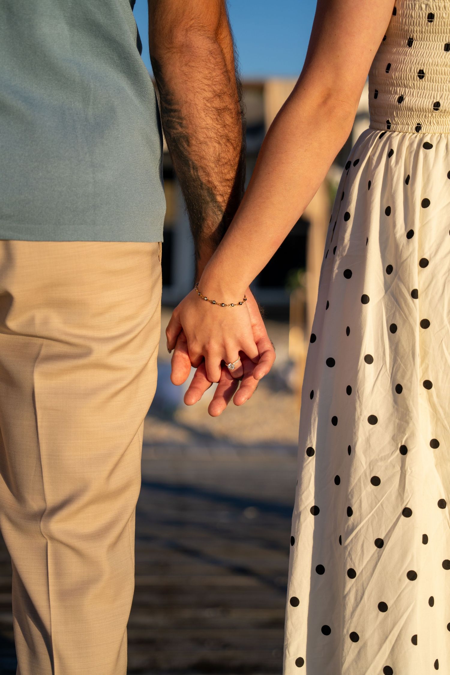 Detail shot of couple holding hands, showing polka dot dress and khaki pants.