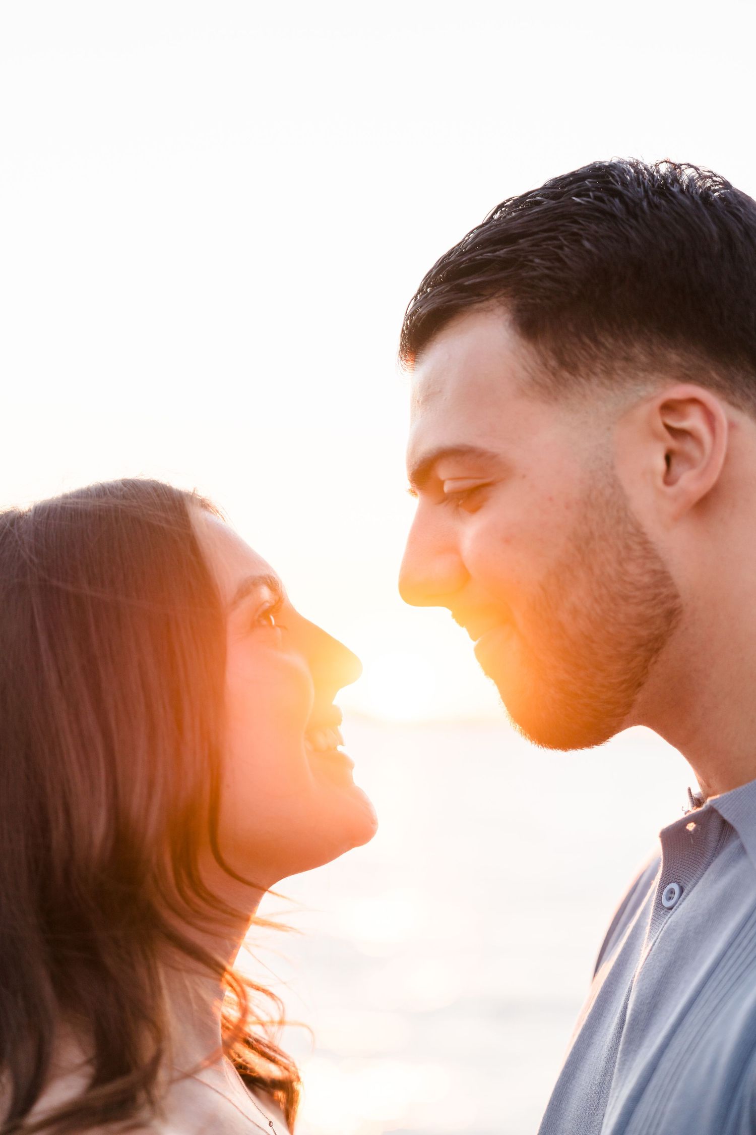 Backlit profile silhouettes of couple against warm sunset glow.