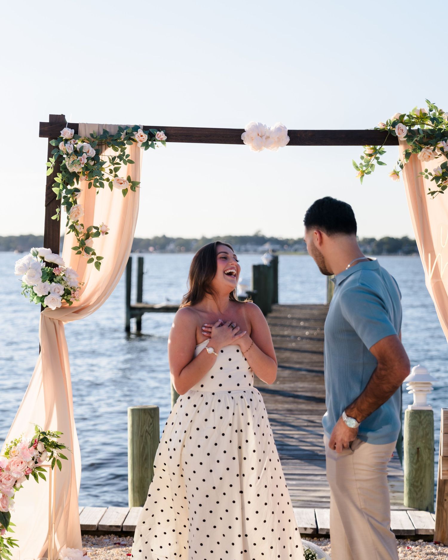 Emotional reaction captured during a surprise beach proposal under a decorated arch.