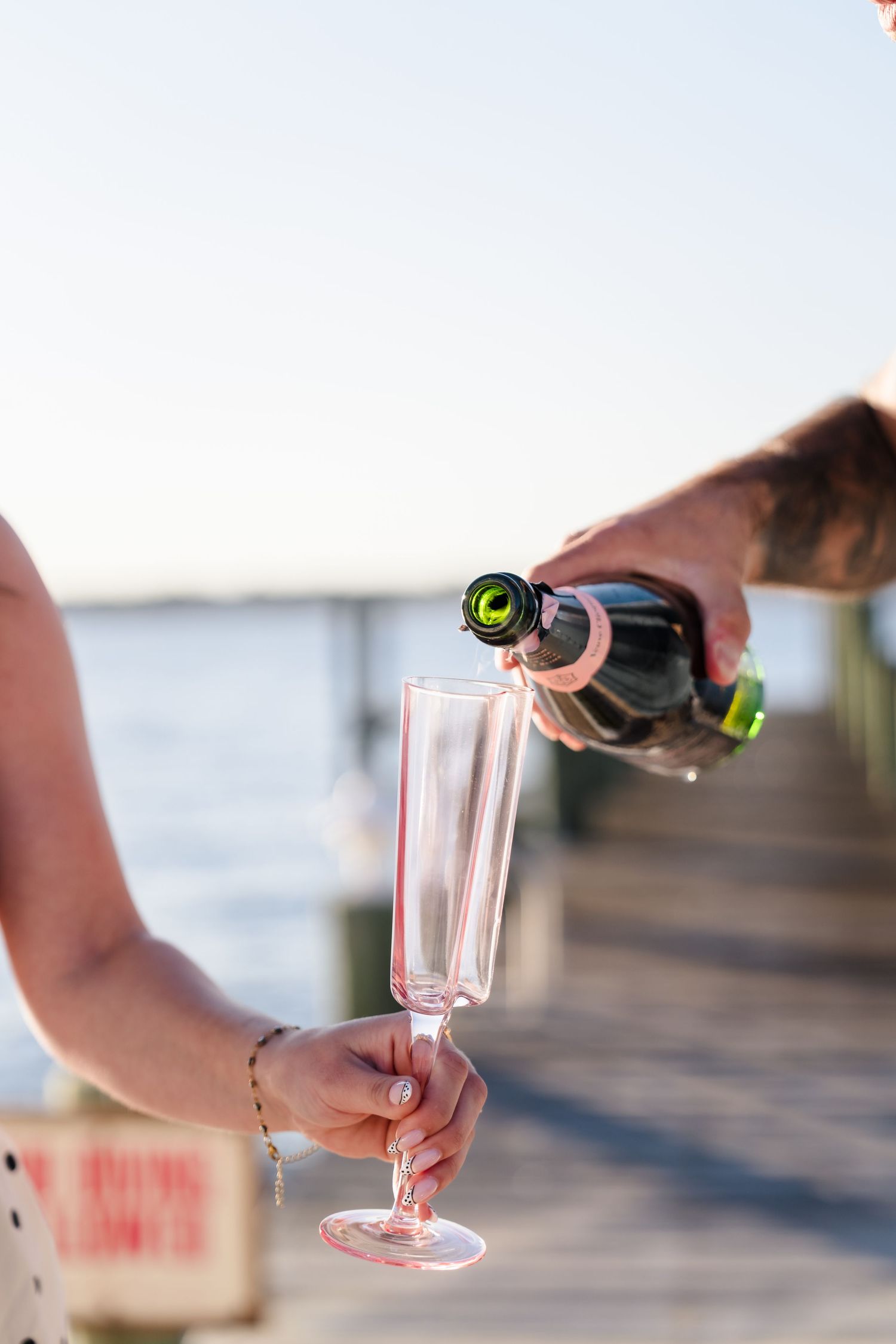 Champagne being poured into glasses during a beachside celebration.