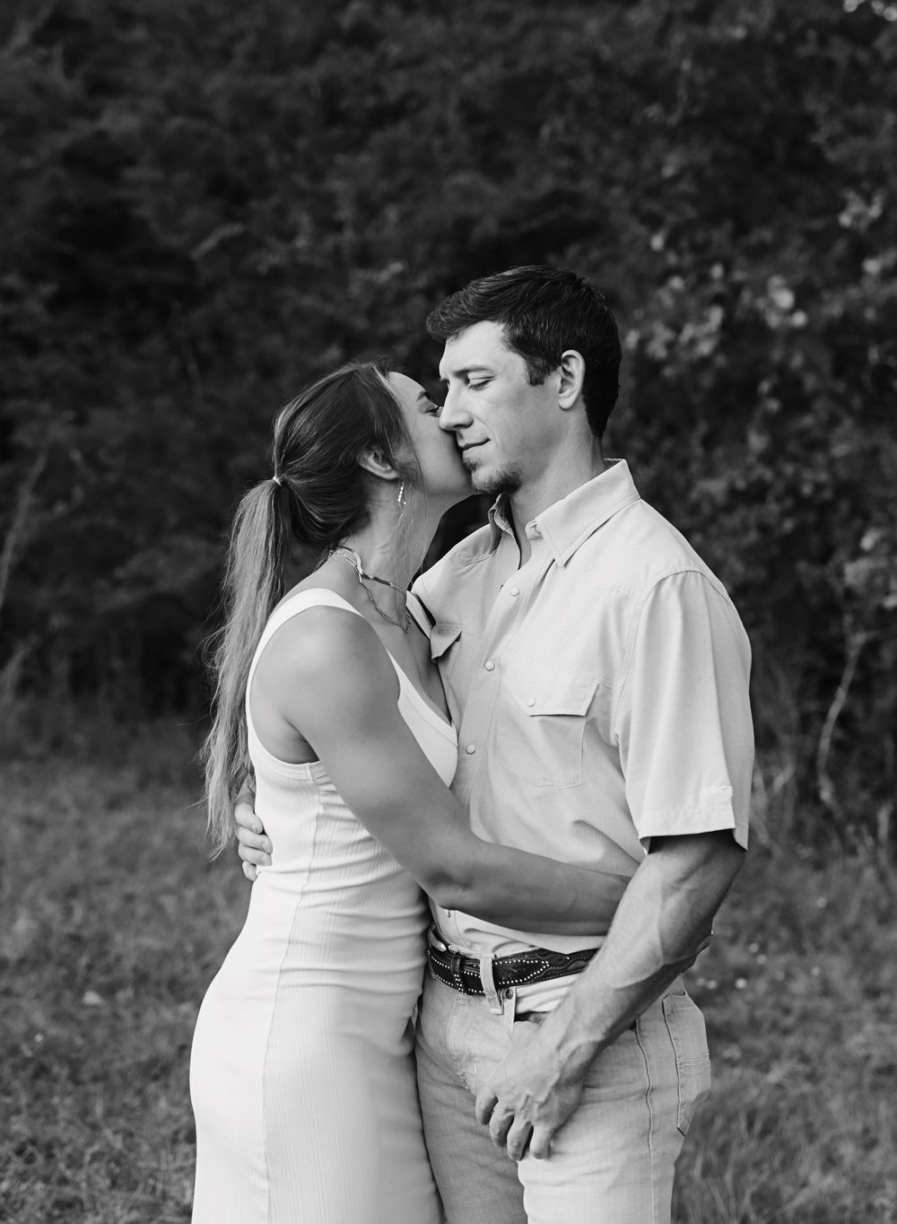 A romantic black and white photo series showing a couple embracing outdoors in a natural setting.