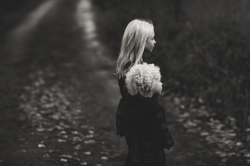 A series of black and white photos showing a person walking through a moody forest setting with fallen leaves.