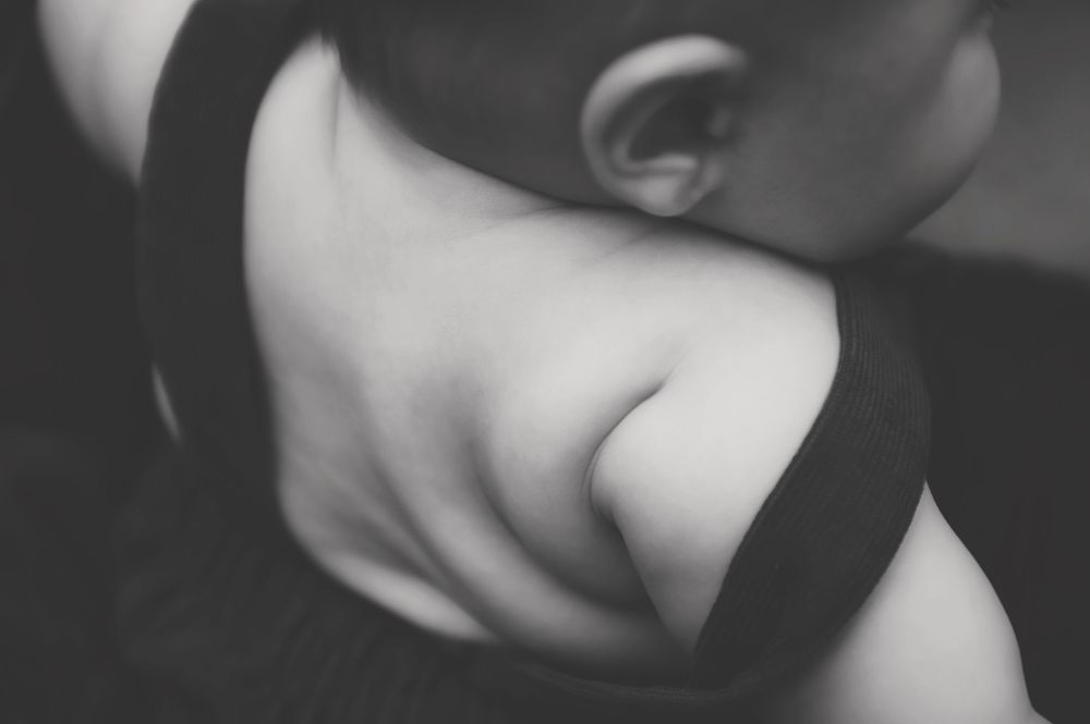 Black and white artistic close-up photograph showing curves of neck and shoulder in dramatic lighting.