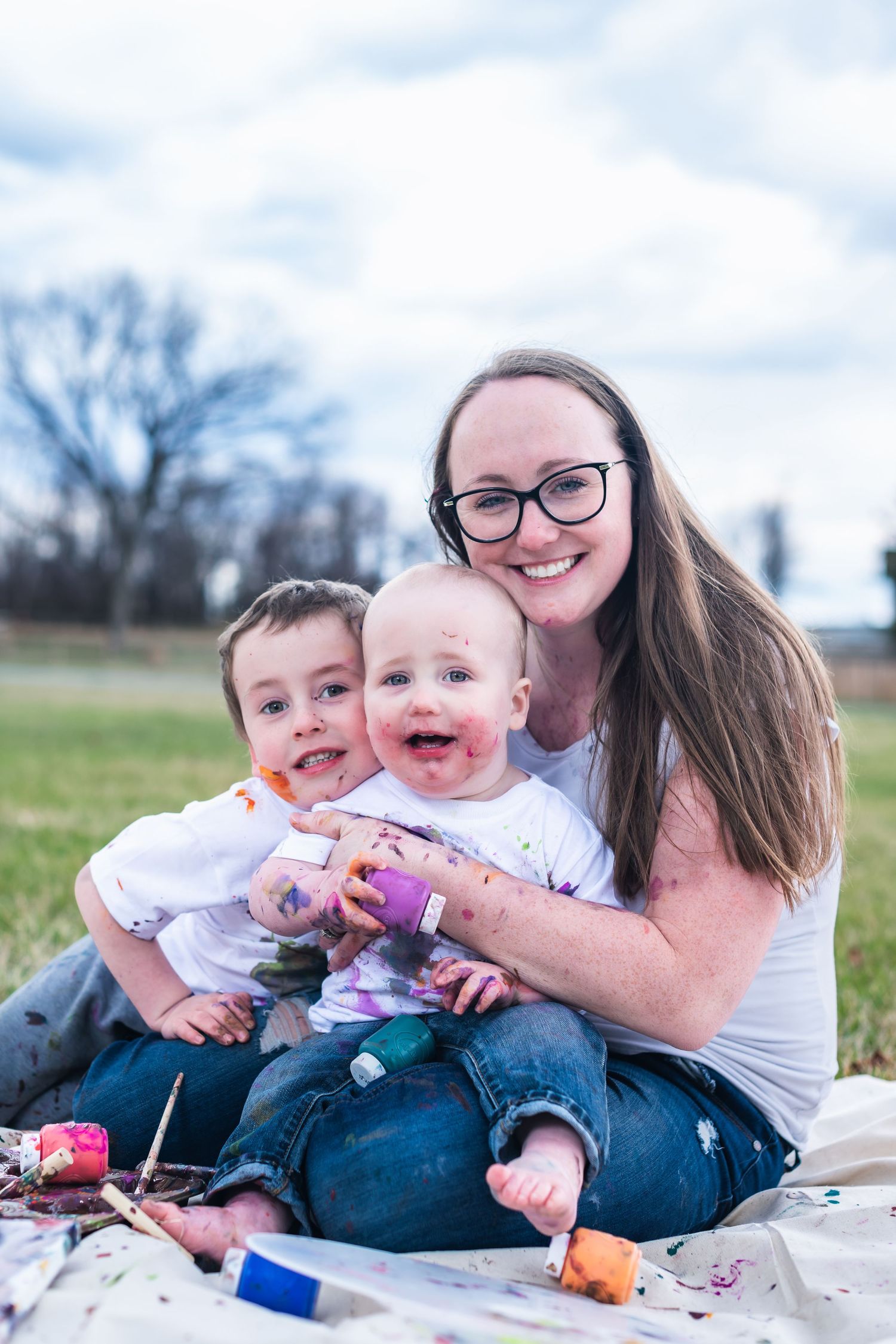 Happy family enjoying a picnic together on a blanket in a grassy field on a sunny spring day.
