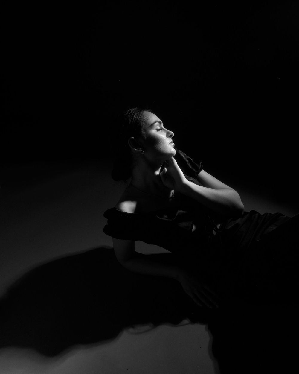 A dramatic black and white artistic portrait with high contrast shadows and highlights.