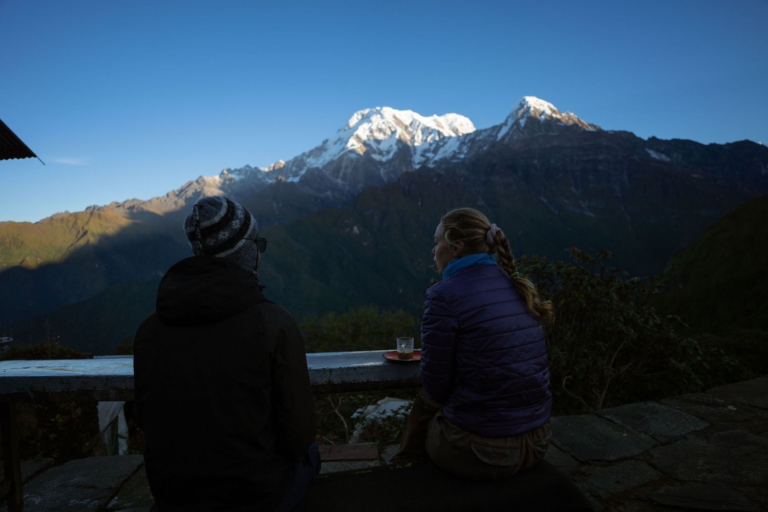 Snow-capped mountain peaks rise against a blue sky in a dramatic mountain landscape.