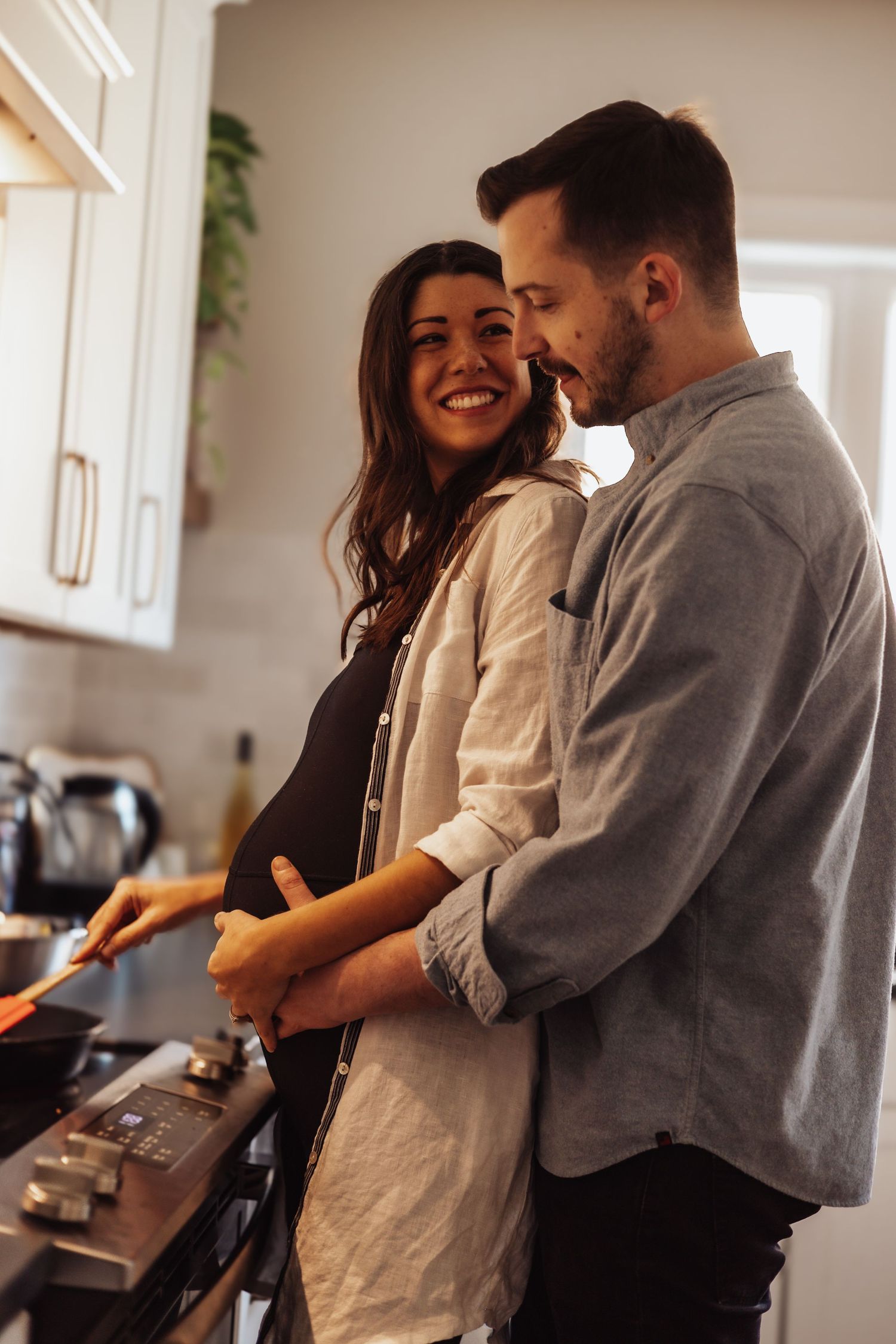 A happy couple shares a tender moment while cooking together in their bright modern kitchen.
