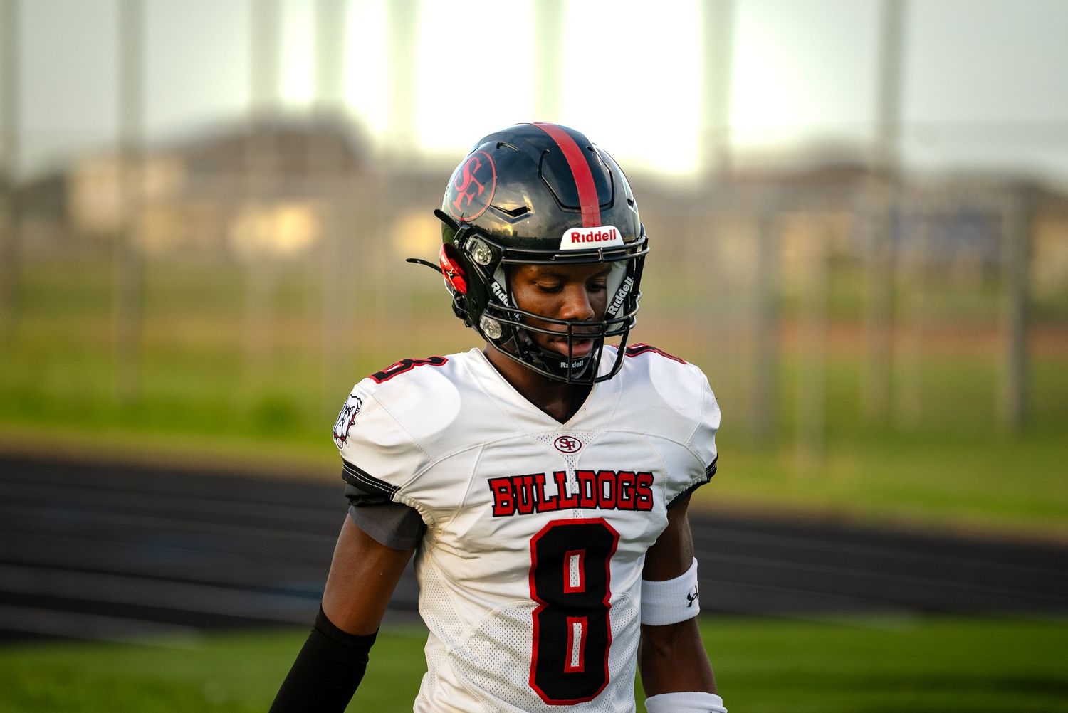 Football player in white and red uniform standing on field during practice.