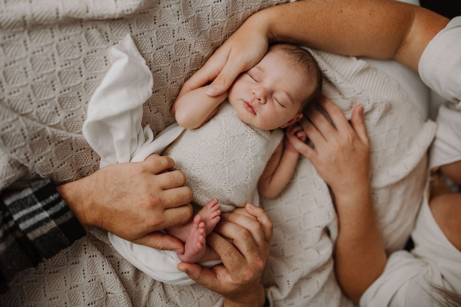 Parents cuddling their newborn baby during a cozy in-home lifestyle photography session in Westport.