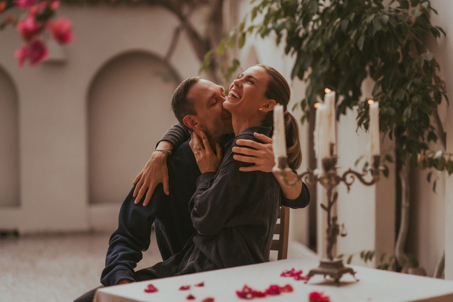 A couple shares an intimate moment during their wedding ceremony in an elegant courtyard with pink floral decor.