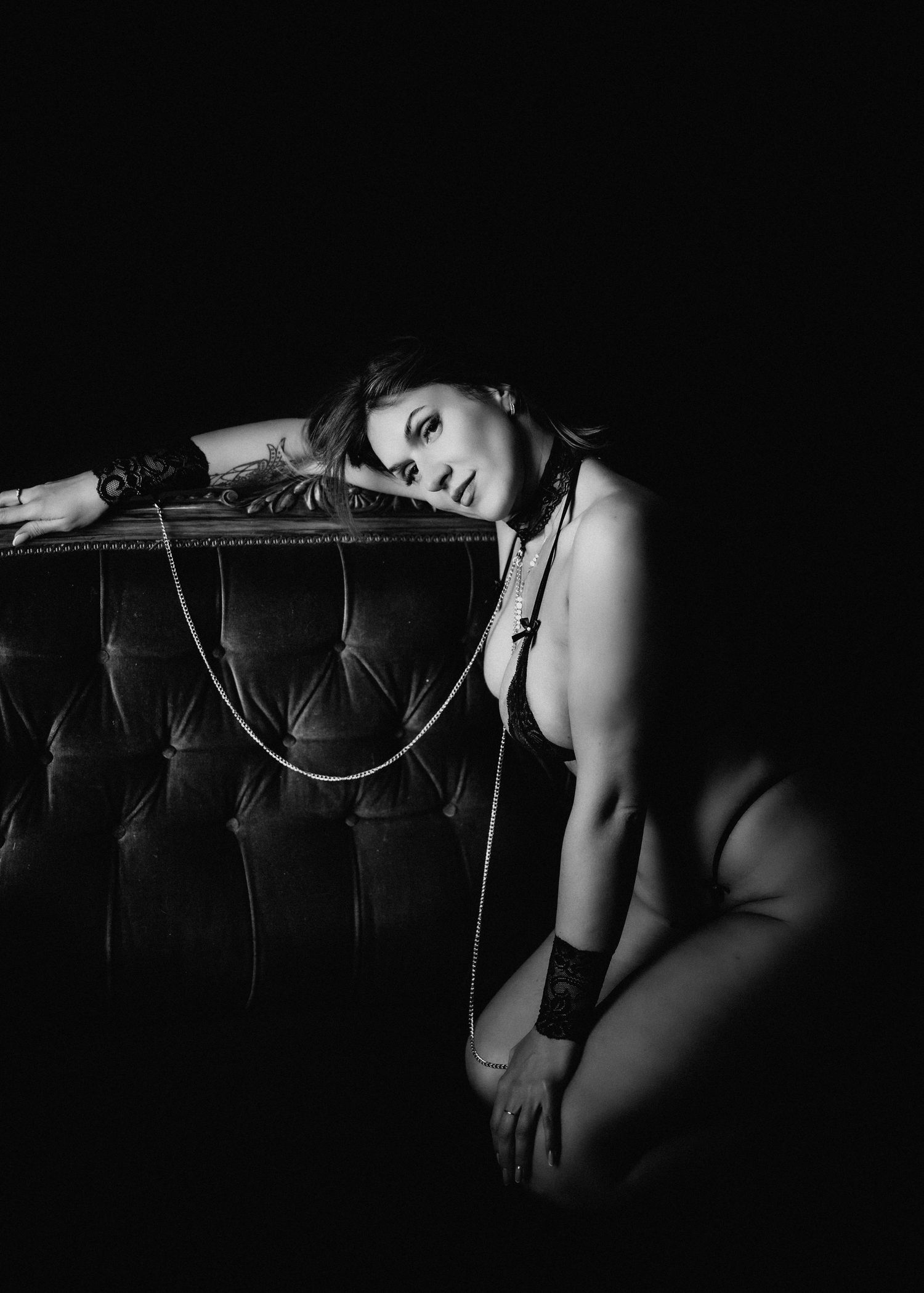 Artistic black and white boudoir photo with a vintage tufted couch.