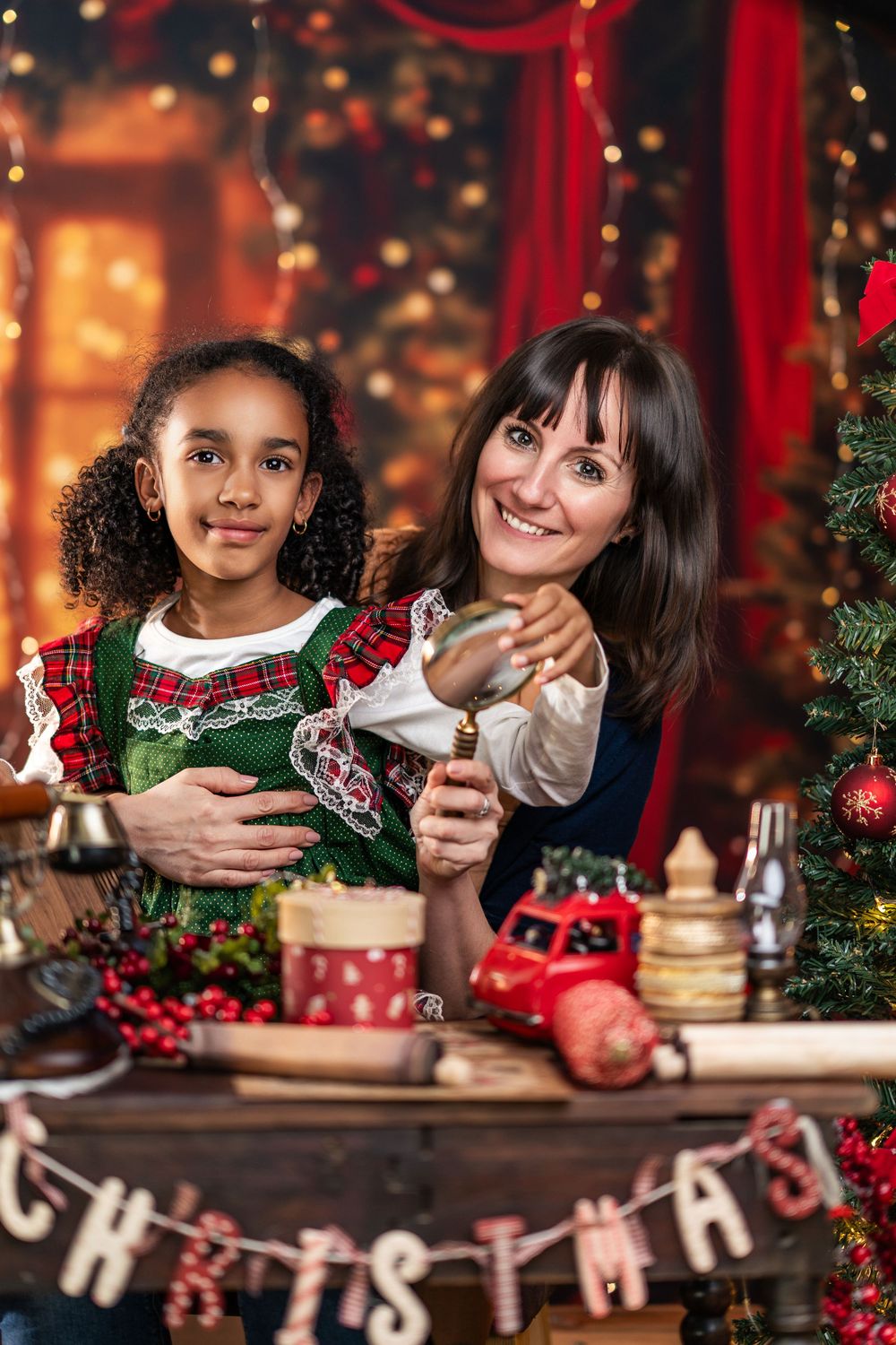 Children wearing festive sweaters gather around a wooden table decorated with Christmas ornaments and berries in a cozy setting.
