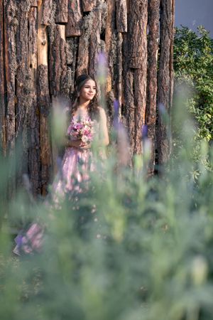 Dreamy portrait through purple wildflowers with wooden tree backdrop.