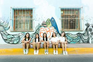 Group sitting against colorful mural wall with ocean waves design.