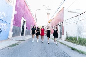 Group walking together down a colorful street with pink and purple painted walls.