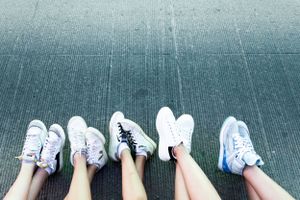 Five pairs of trendy sneakers lined up in a row on a concrete surface showing different styles and colors.