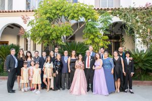 Large group poses together at outdoor venue with arched architecture and lush greenery.