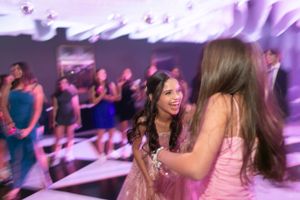 Guests enjoying dance floor at reception with purple ambient lighting.