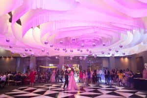 Elegant ballroom with pink uplighting and draped fabric ceiling during a wedding reception.