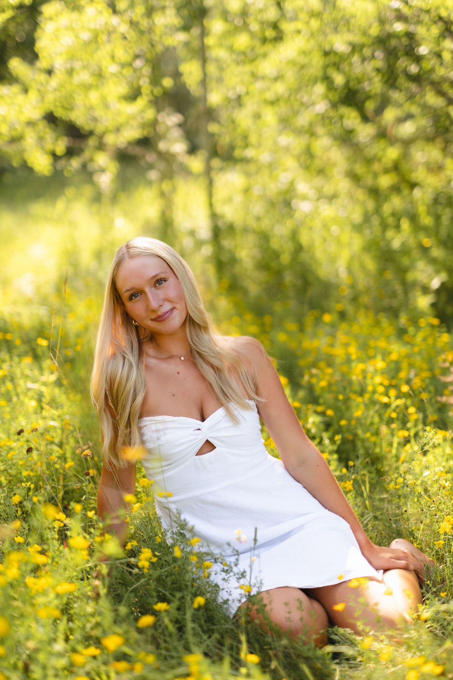 A person in a white dress lies in a sunny meadow filled with bright yellow wildflowers on a summer day.
