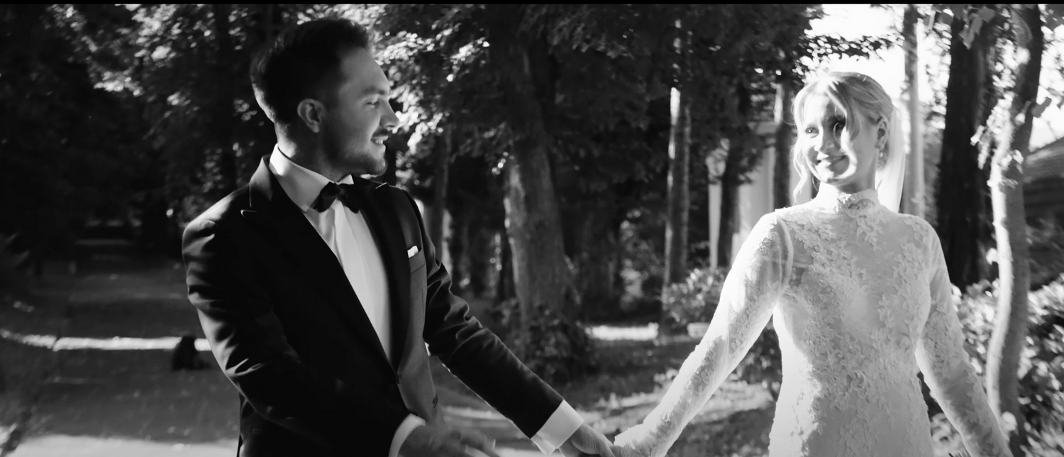 Elegant black and white portrait of newlyweds dancing together in a forest setting.