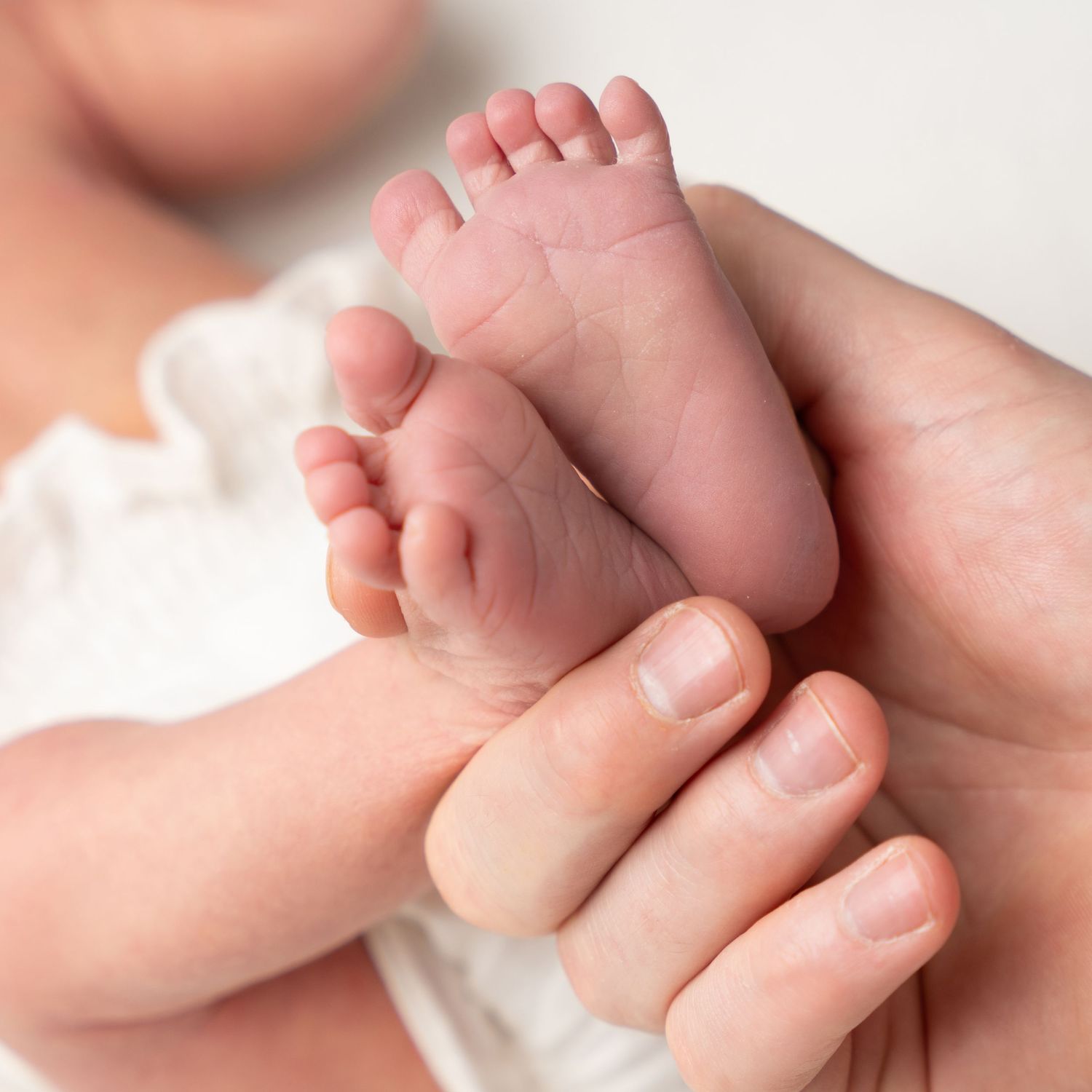 Close-up of tiny baby feet being gently held by adult hands.