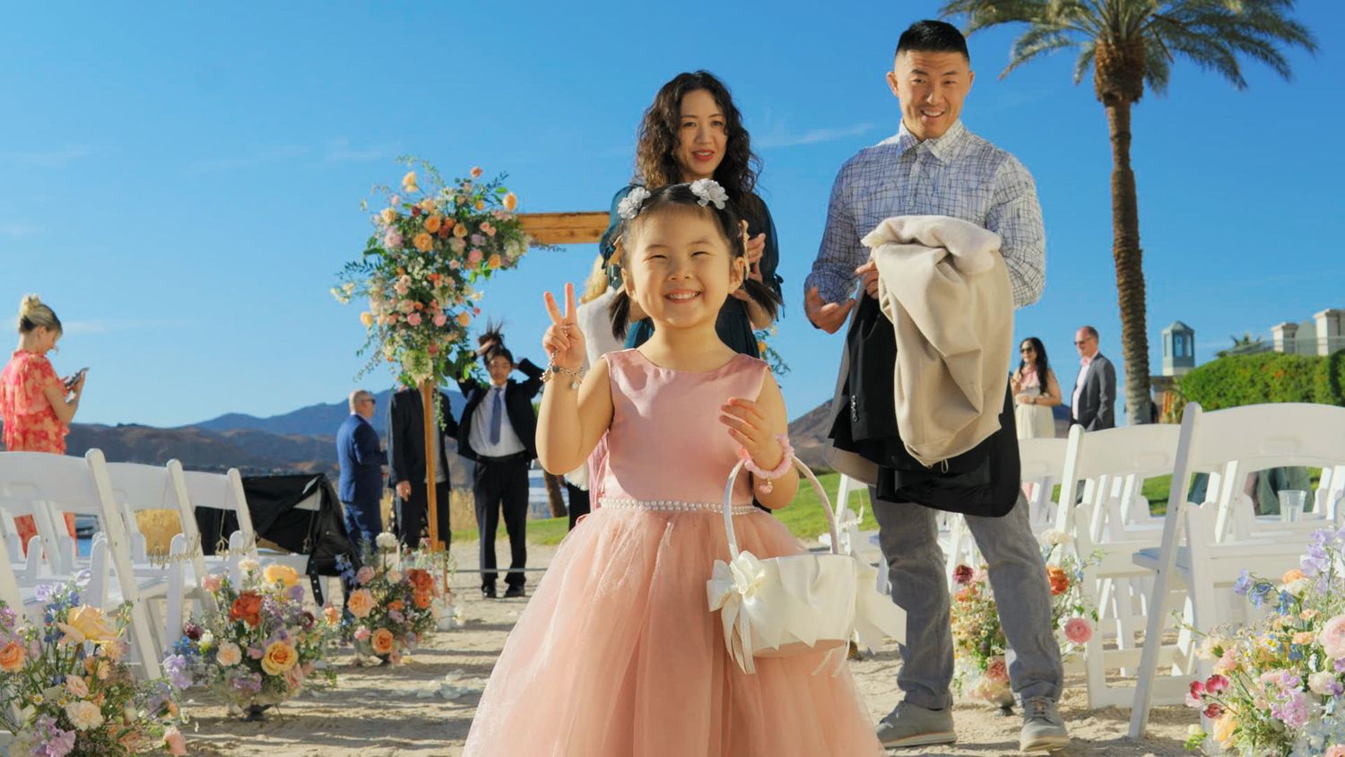 Outdoor celebration setup with chairs and floral decorations against mountain backdrop.