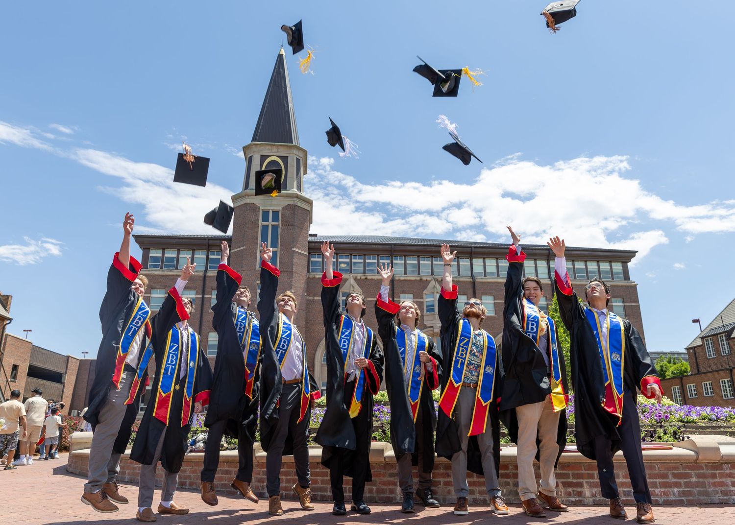 Graduates of the University of Denver celebrate their graduation day with a graduation cap toss, captured by Denver senior photographer.