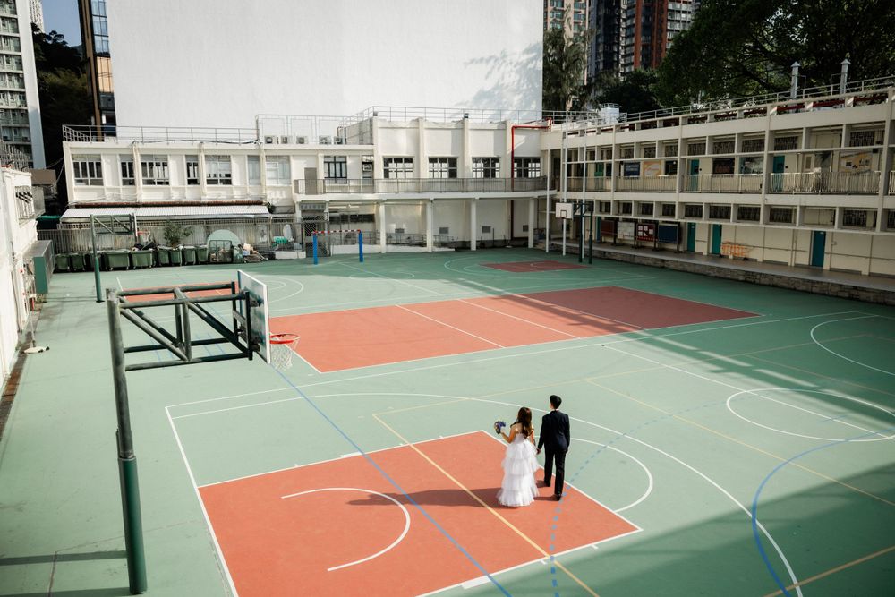 Bride and groom standing together on a colorful rooftop basketball court in an urban setting.