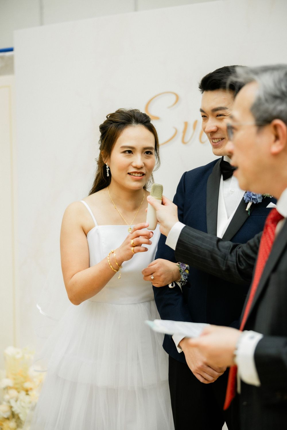 Bride smiles as officiant places ring on her finger during intimate wedding ceremony.