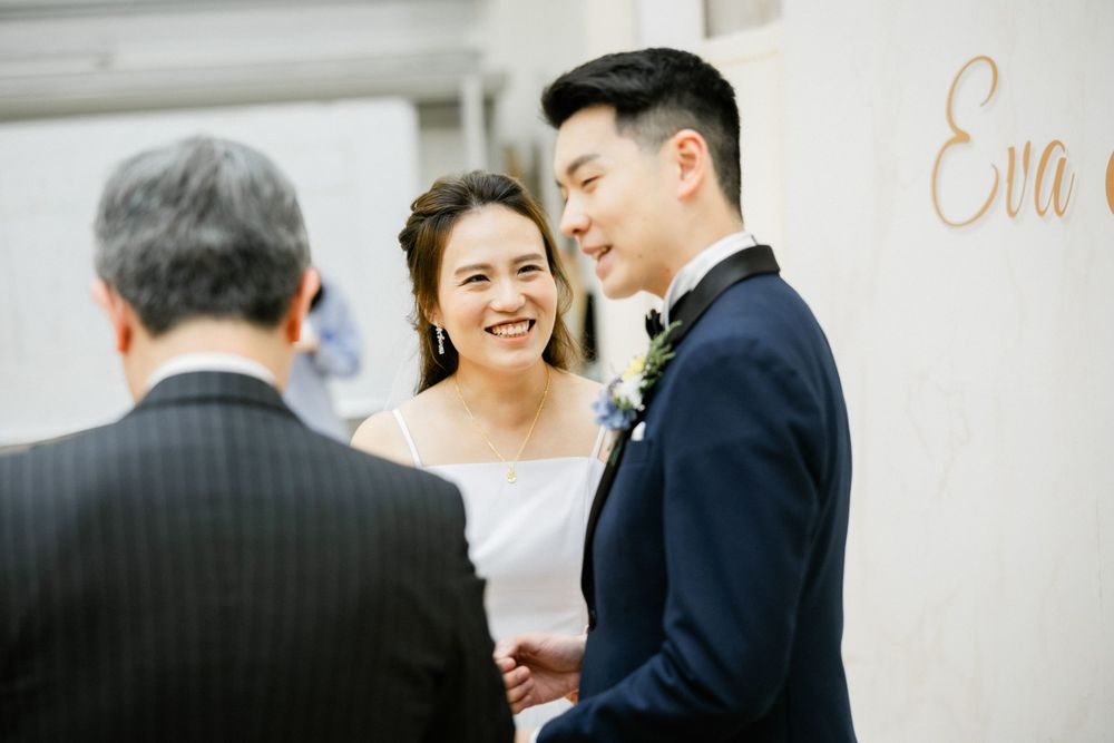 Bride laughs joyfully with groom during wedding ceremony near Eva name sign backdrop.