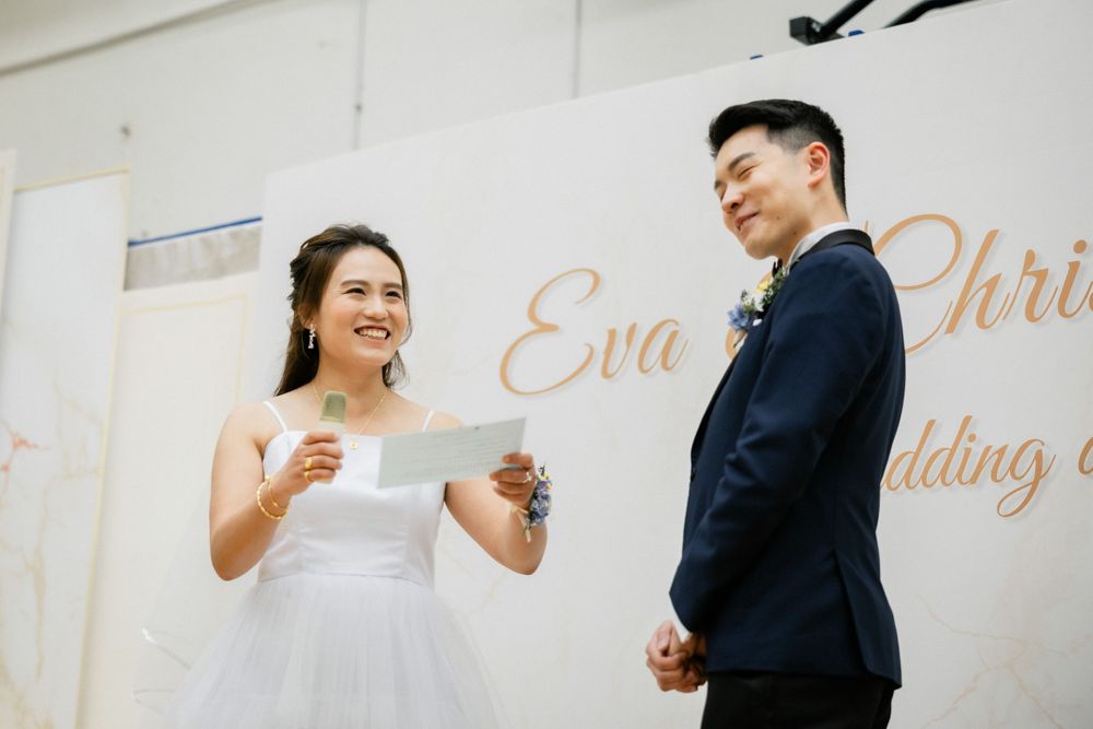 Bride reads wedding vows from card while holding grooms hand at Eva and Chris wedding.