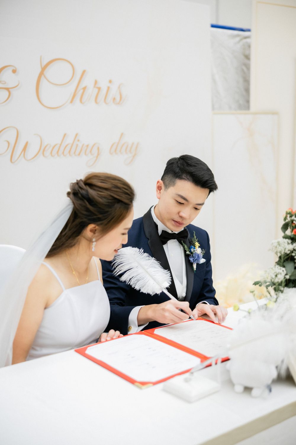 Bride and groom Chris sign their wedding certificate with a feather pen at the ceremony.