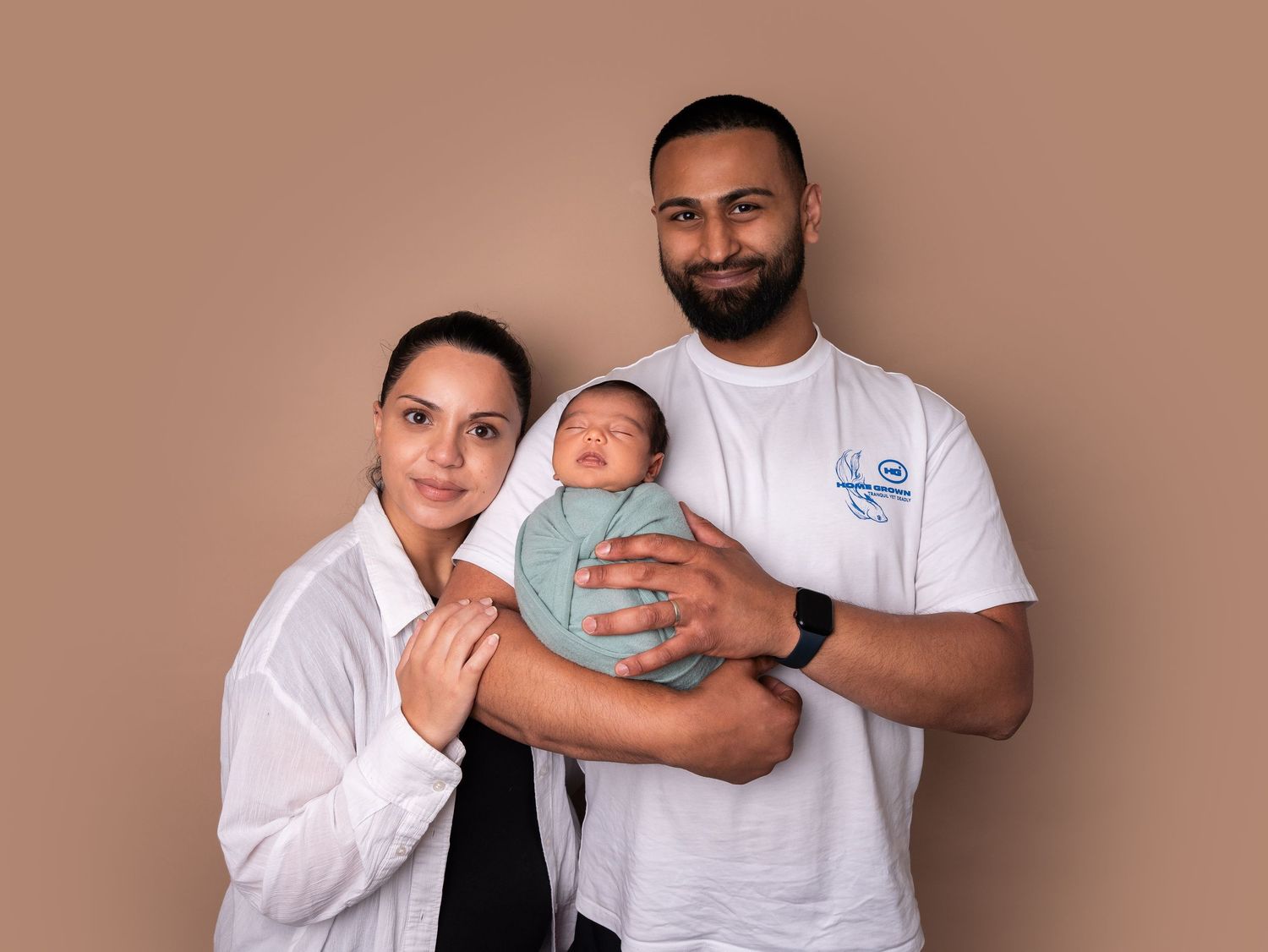 Parents and baby, Family photo holding newborn baby boy wrapped in green blanket by newborn photographer in Doncaster.